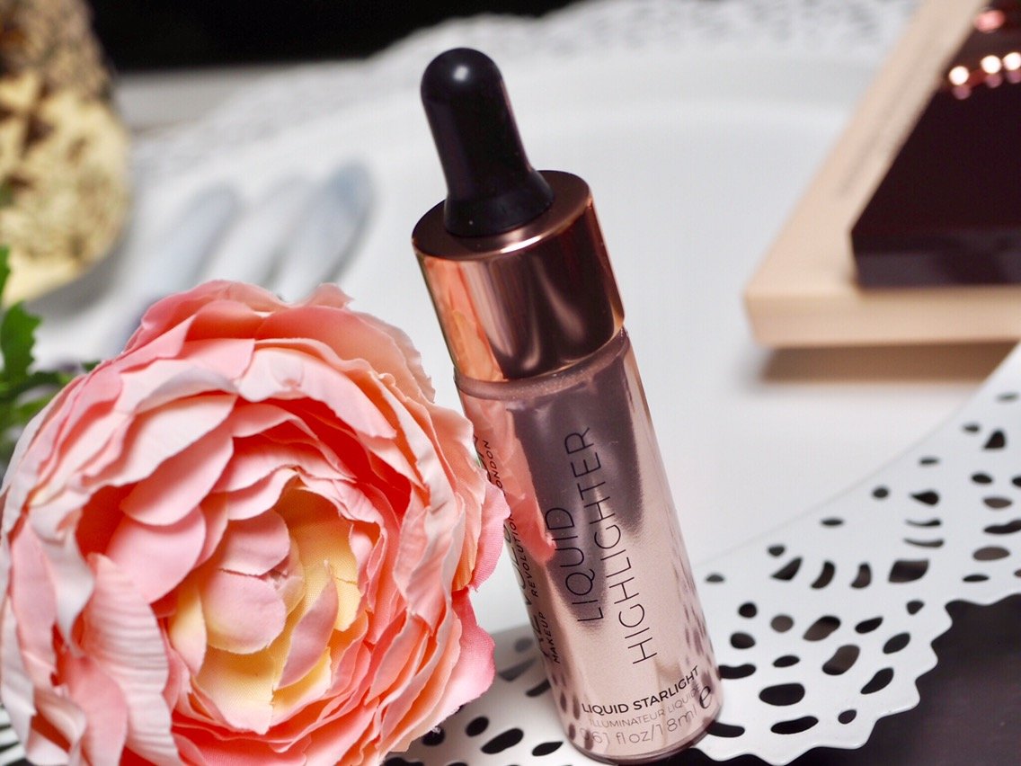 Makeup Revolution Liquid Highlighter Review- pretty gold metallic dropper bottle next to a flower